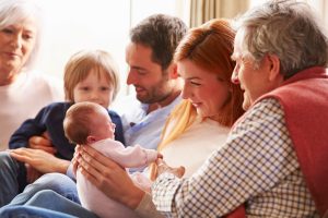 Multi Generation Family Sitting On Sofa With Newborn Baby
