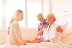 family visiting ill senior woman at hospital