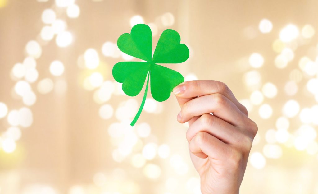 hand holding green paper four-leaf clover